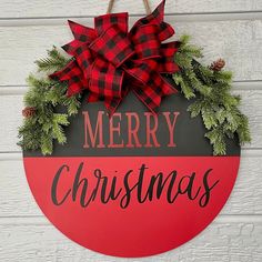 a merry christmas sign hanging on the side of a white wooden wall with evergreen and pine cones