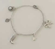 This Coastal Cowgirl Silver Charm Bracelet is the perfect accessory for every outfit. This dainty bracelet boasts an eclectic mix of charms, including a cowgirl boot charm for the coastal cowgirl, a delicate heart charm, a chic bow charm, a radiant star charm, and a seashell charm that ties all the pieces together. Get this charm bracelet for everyday wear or for the perfect gift! Charm Jewelry Silver, Silver Charm Bracelets, Silver Charm Bracelet Aesthetic, Adjustable Metal Charm Bracelet, Cute Style, Charm Bracelet Silver, Silver Charm Bracelet For The Beach, Themed Silver Charm Bracelet, Silver Adjustable Charm Bracelet For Beach, Western Charm Bracelet