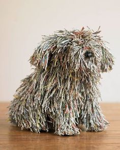 a dog made out of newspaper sitting on top of a wooden table