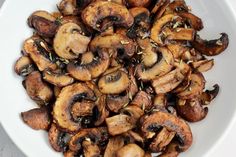 a white bowl filled with sliced mushrooms on top of a table