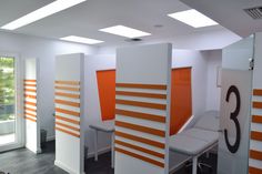 an office cubicle with orange and white dividers, desks and chairs in it