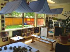 a room filled with lots of windows covered in blue curtains and artwork on the walls