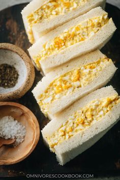 several pieces of rice bread on a black plate next to some bowls and spoons