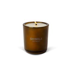 a candle that is sitting in front of a white background with the words shinola detroit on it