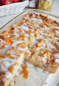 a close up of a cake on a pan with apples in the bake behind it