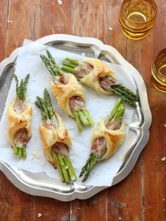 asparagus and prosciutto wrapped in puff pastry on a silver platter