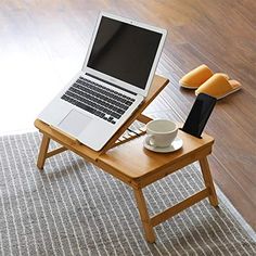 an open laptop computer sitting on top of a wooden table next to a coffee cup