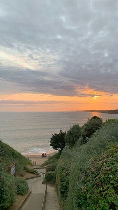 stairs lead down to the beach as the sun sets over the ocean in the distance