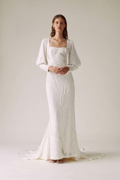 a woman in a white wedding dress with long sleeves