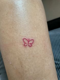 a small pink butterfly tattoo on the back of a woman's leg and arm