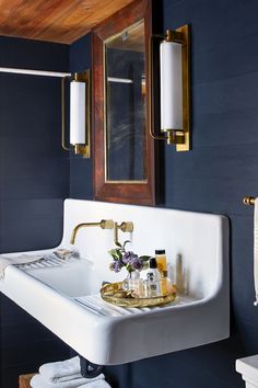 a white sink sitting under a bathroom mirror next to a wooden framed wall mounted mirror