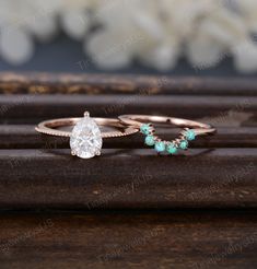 two rings with turquoise stones on them sitting next to each other in front of a wooden surface