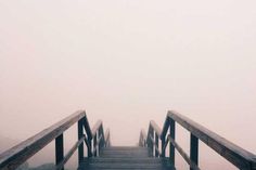 a wooden bridge going into the foggy sky