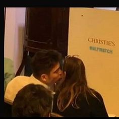 a man and woman are kissing in front of a white box with the words christes on it