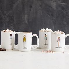 three coffee mugs with different characters on them and marshmallows in front