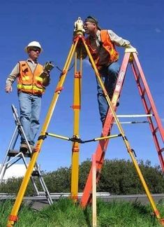 two men standing on top of a ladder next to each other