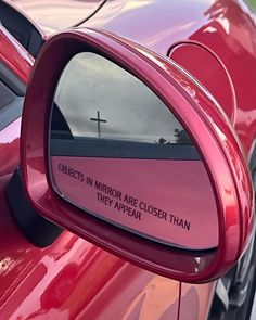 a red car with a cross on it's side mirror and the words objects in mirror are closer than they appear