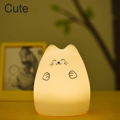 a cat shaped light sitting on top of a wooden table next to a framed photo