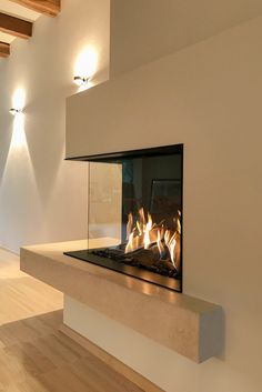 a fire place in the middle of a room with wood floors and lights on either side