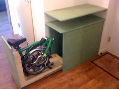 a bicycle is parked in the corner of a room with a green desk and shelf