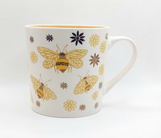 a yellow and black coffee cup with bees on it