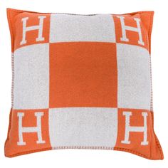 an orange and white pillow with the letter h on it