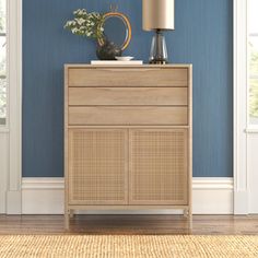 a wooden cabinet with a lamp on top in front of a blue wall and hardwood floor