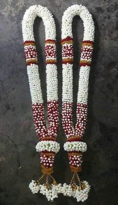 white and red beaded necklaces with tassels hanging from them on a black surface