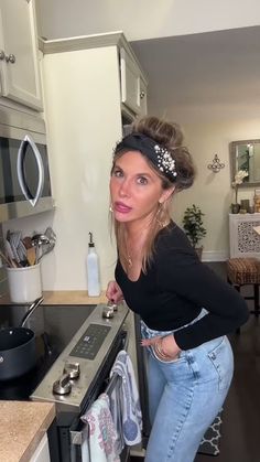 a woman is leaning on the stove in her kitchen