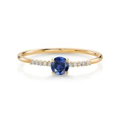 a yellow gold ring with an oval blue sapphire and white diamonds on the side, set in