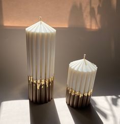 two white and gold candles sitting next to each other