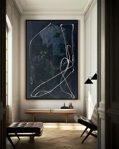 a black and white abstract painting hangs in the corner of a room with a bench