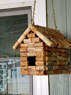 a birdhouse made out of wine corks hanging from a door frame with chains