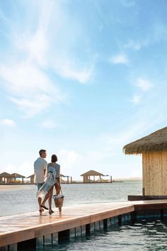 two people standing on a dock looking out at the water