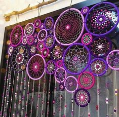 purple and pink dream catchers are hanging on the wall in front of a window