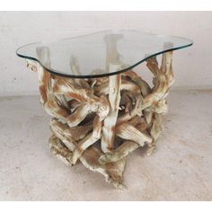 a glass top table made out of driftwood on a white floor with a beige wall behind it