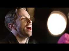 a man singing into a microphone in front of a bright light that is shining on him