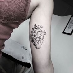 a woman's arm with a flower and heart tattoo on the left side of her arm