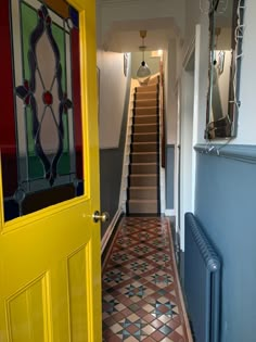 the hallway is painted bright yellow and has an ornate glass panel on the door, along with matching tile flooring