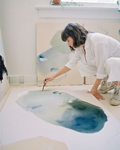 a woman is painting on the floor in her home