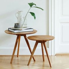 two small wooden tables sitting on top of a hard wood floor next to a plant