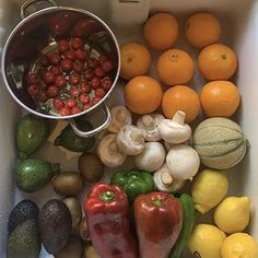 an assortment of fruits and vegetables sitting in a sink next to lemons, tomatoes, avocados, peppers, oranges, and other fruit