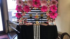 a table topped with lots of pink flowers next to a black and white striped wall