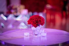 red roses in a vase on a table with ice cubes and candlelight background