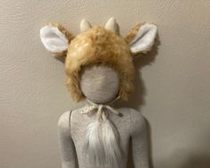 a stuffed animal wearing a white dress and headdress with horns on it's ears