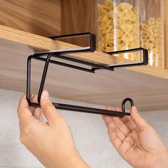 two hands are holding the handles on a shelf