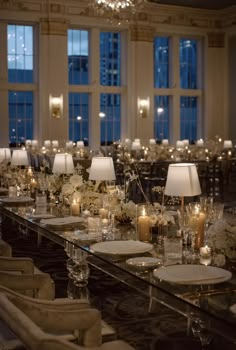 a long table with candles and flowers on it in a large room filled with windows