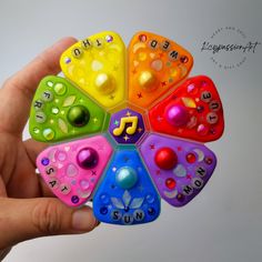 a hand holding a multicolored toy with letters and numbers in it's center