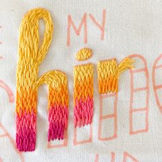 an embroidered piece with the words i love you written on it and two different colored yarns