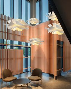 two chairs and a table in front of a wooden wall with lights hanging from it